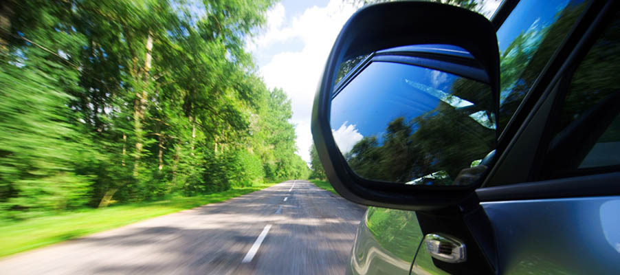 Car driving down the road. Reflection view of side mirror.