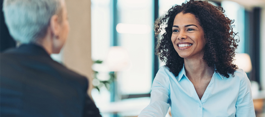 Woman smiling at another person in an office setting.